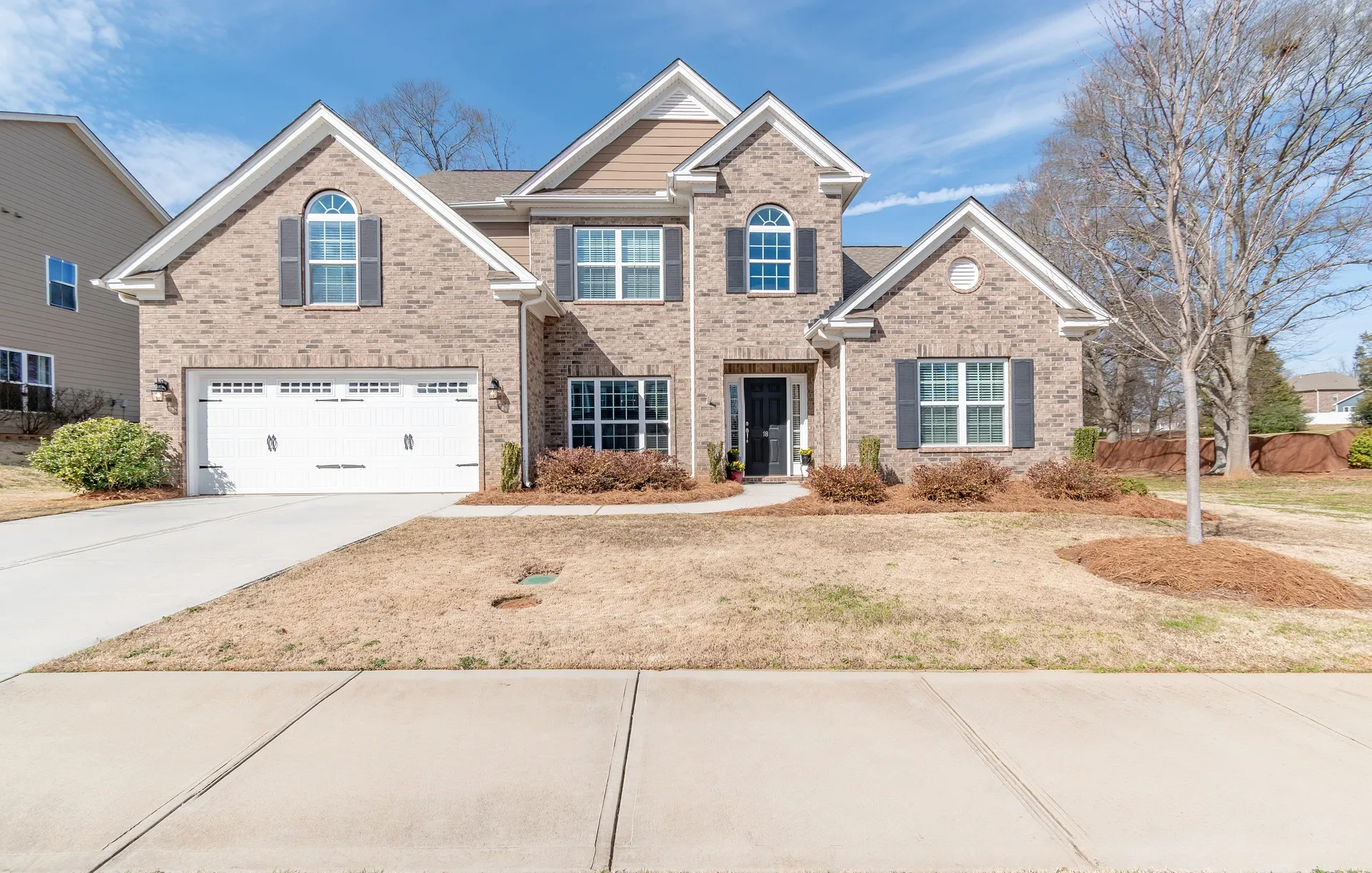 Beautiful brick two-story home with a garage and well-maintained yard, showcasing residential construction expertise.